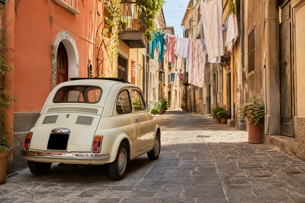 Fiat 500 restaurée stationnée dans une ruelle pavée d’un village italien